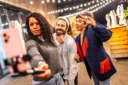 Friends gesturing success while streaming online video with smartphone during party at night outdoors